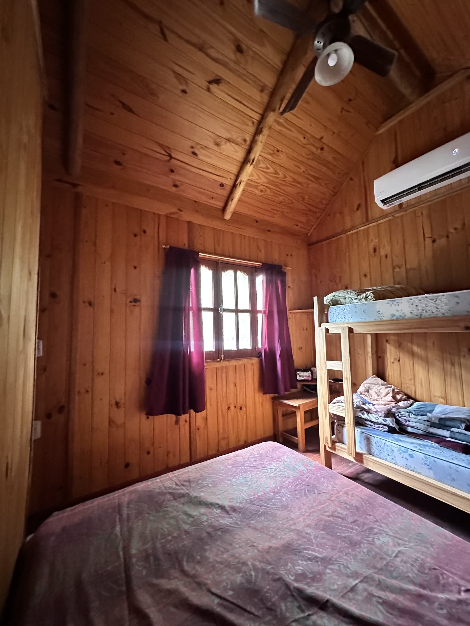 Cucheta de madera junto a la cama principal, con ventilador de techo y aire acondicionado
