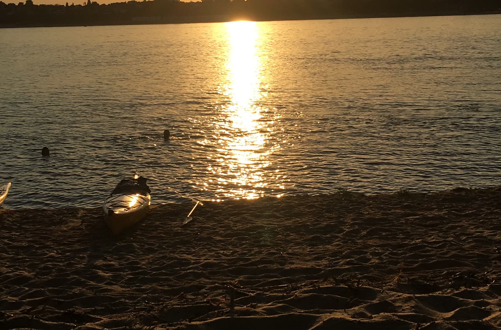 Kayak en la orilla del Paraná al atardecer, con el reflejo del sol sobre el agua